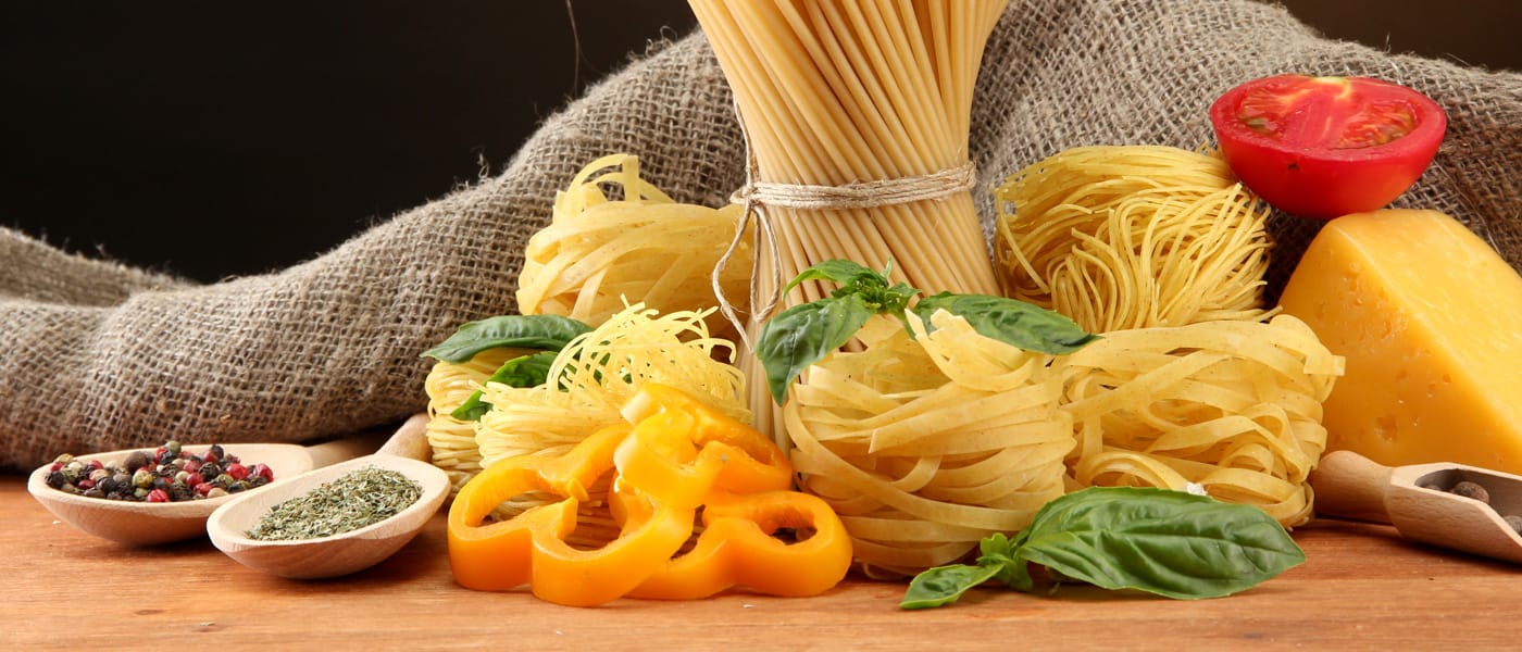 Stilleven van verse pasta, basilicum, tomaat en kaas op een houten werkblad