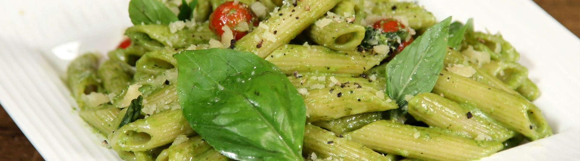 Bord verse penne met pesto, parmezaan en basilicum, opgediend